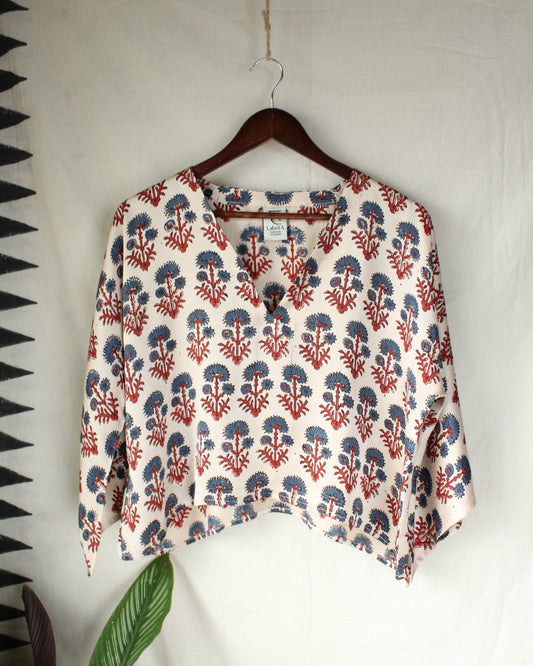 Floral patterned blouse on a hanger against a white wall