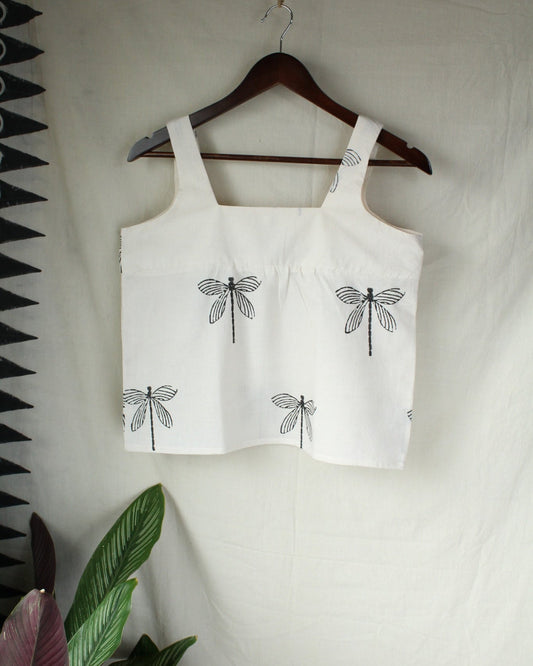 White tank top with black dragonfly designs on a hanger against a white background